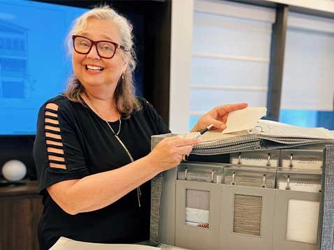 A smiling woman presenting some fabric samples