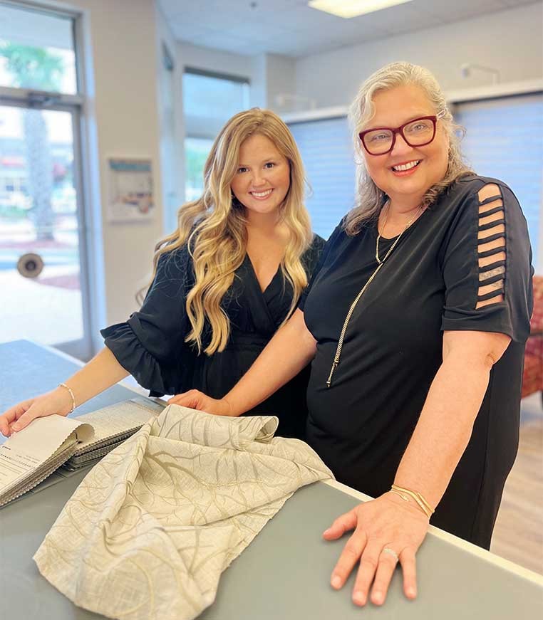 two smiling women working with drapery